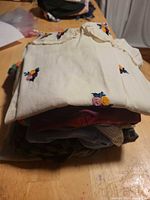 Stack of tops topped by cream embroidered blouse