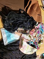 Overall view showing knit hat, lace bra, two bikini tops, sealed headband package, black silk belt