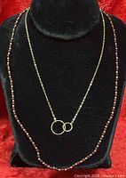 Necklaces displayed on black bust, garnet strand and gold chain visible