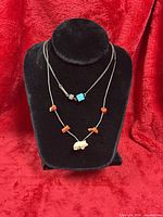 Both necklaces displayed on stand