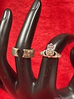 Two sterling silver rings displayed on black hand form