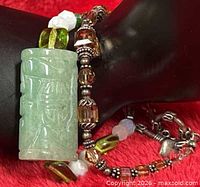 Jade bracelet wrapped around display showing carved jade barrel focal and mixed beads