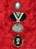 Front view of all four brooches arranged vertically on red fabric