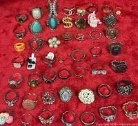 overview of 50 assorted costume rings laid out on red fabric