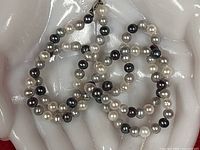 Close-up of strand showing white, grey, black pearls and clasp