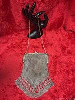 Full view of silver-tone metal mesh purse hanging from chain handle