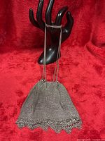 Front view of silver-tone metal mesh purse hanging from display hand