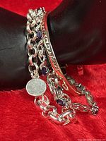 Close-up of bracelets showing chain links, glitter charm, purple beads, engraved bangle