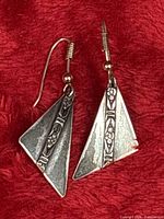Pair of sterling silver triangular earrings on red background