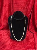 Full view of the white pearl necklace on black display bust