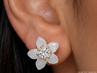 Earring worn on ear showing scale, 14K gold setting with diamond and flower jacket