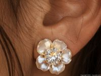 Single earring worn showing flower shape and diamond center