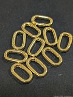 Group of ten oval gold-plated key ring bails displayed on dark background