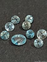Nine loose blue topaz gemstones on black background