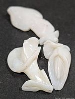 Three carved white opal pieces on black background