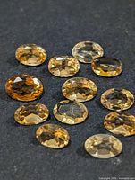 Group of 12 oval faceted citrine gemstones on dark background