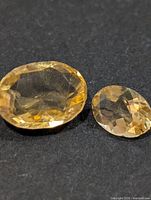 Two faceted citrine gemstones on black background