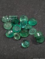Group of small green emerald gemstones on black surface