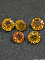 Close view of five faceted round sapphires showing color and cut