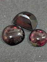 Three garnet stones grouped on dark surface