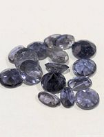 Group of faceted bluish-violet Iolite gemstones on neutral background