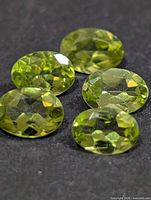 Close-up of five faceted peridots showing color and cut