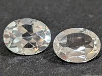 Two oval faceted transparent stones on black background
