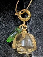 Overall view of quartz flower pendant and green charm on gold-tone jump ring