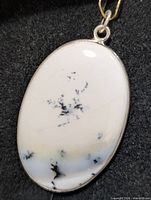 Front view of oval dendritic opal pendant in silver bezel