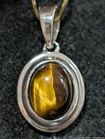 Front view of silver pendant with tiger eye cabochon