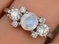 Close-up of ring on finger showing moonstone and surrounding CZ stones