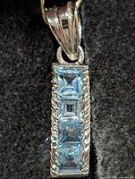 Front view of silver pendant showing four blue topaz stones