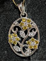 Front view of silver pendant with yellow and clear CZ floral motif