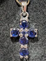 Front view of silver cross pendant with six blue stones