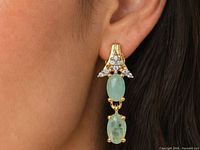 Earring on ear showing scale, two emerald cabochons and CZ cluster