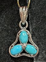 front view of silver pendant with three turquoise stones