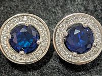 Front view of both stud earrings showing sapphire centres and CZ halo