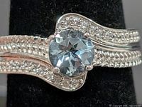 Front view of sterling silver ring with blue topaz centre and CZ accents