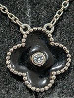 Close-up of pendant front showing black enamel quatrefoil, beaded border and centre stone