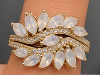Ring on finger showing overall design with marquise moonstones and pavé CZ in yellow gold-tone setting