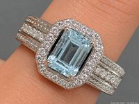 Ring on finger showing top view of blue topaz, CZ halo, and shank detail
