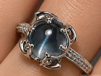 Ring worn on finger showing blue topaz cabochon and CZ-set shoulders