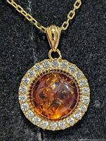 Close-up of pendant front showing amber cabochon and CZ halo