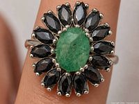 Front view of ring showing emerald centre and sapphire halo