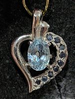 Front view of heart pendant showing blue topaz center and sapphire accent stones