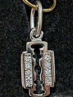 front view of silver-tone razor blade pendant with CZ stones