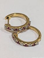 Front view of both hoop earrings showing diamond and ruby settings