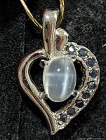 Front view of silver heart pendant showing moonstone and sapphire arrangement