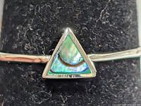 close-up of triangular mother of pearl inlay set in silver bezel