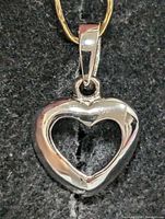 Front view of polished silver heart pendant showing open center and bail